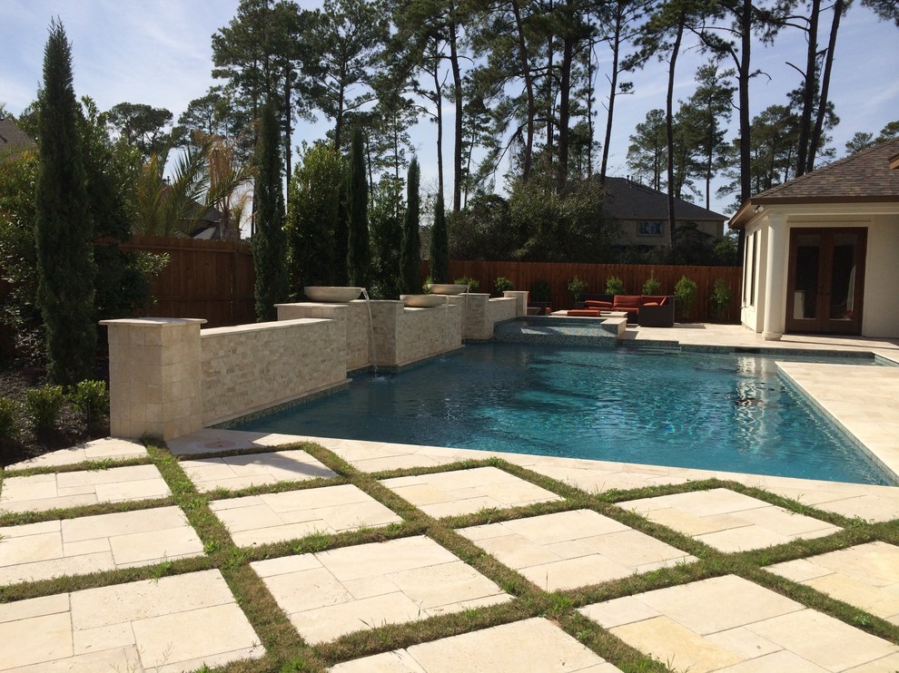 Photo of a mid-sized contemporary backyard custom-shaped pool in Houston with natural stone pavers and a hot tub.