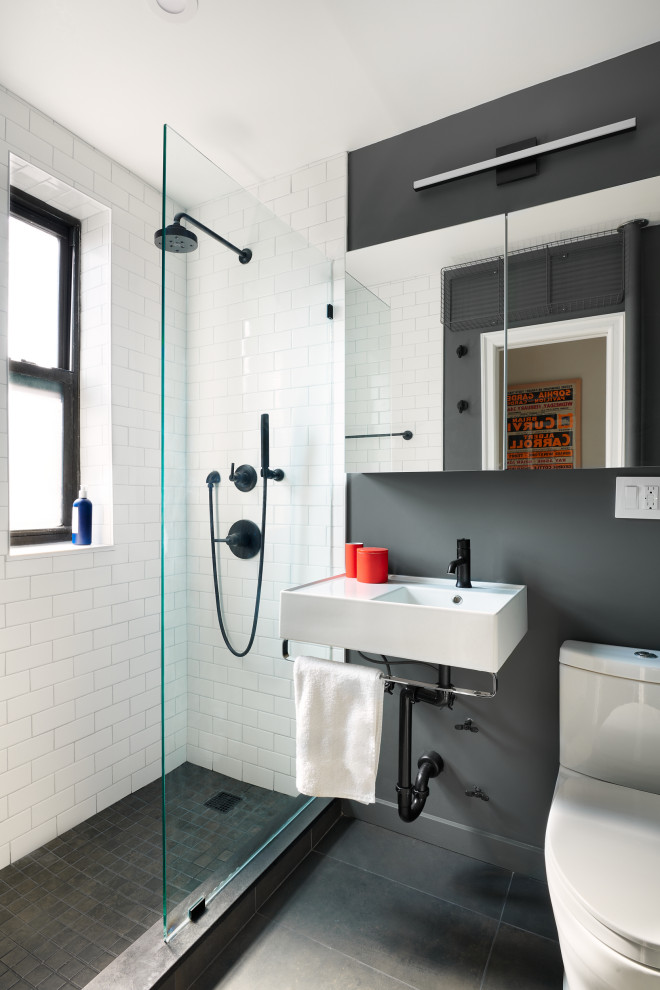 This is an example of a contemporary 3/4 bathroom in New York with white cabinets, an alcove shower, a two-piece toilet, white tile, subway tile, black walls, a wall-mount sink, grey floor, white benchtops, a single vanity and a floating vanity.