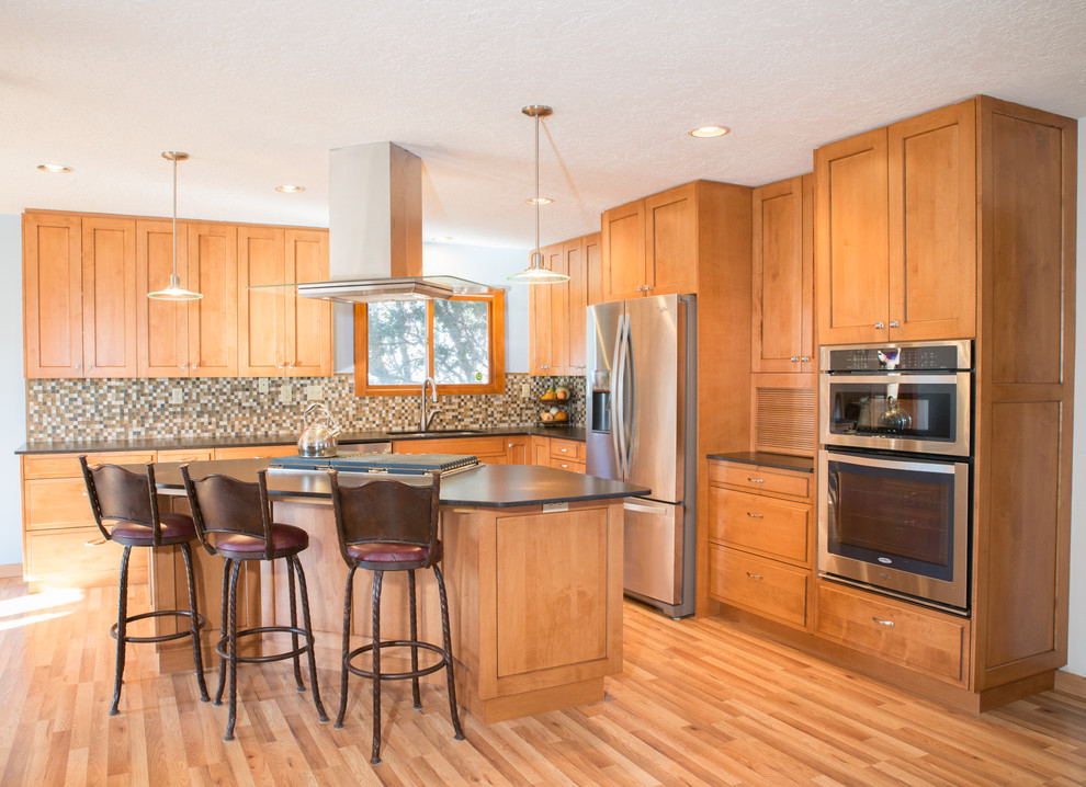 This is an example of a large l-shaped open plan kitchen in Albuquerque with an undermount sink, flat-panel cabinets, medium wood cabinets, quartzite benchtops, brown splashback, mosaic tile splashback, stainless steel appliances, light hardwood floors and with island.