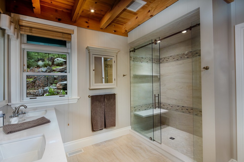 This is an example of a mid-sized country 3/4 bathroom in Toronto with white cabinets, an alcove shower, beige tile, beige walls, ceramic floors, a drop-in sink, granite benchtops, beige floor, a sliding shower screen and white benchtops.