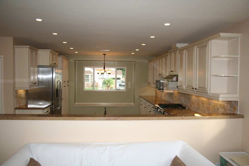 Large transitional u-shaped kitchen photo in Orange County with raised-panel cabinets, white cabinets and stainless steel appliances