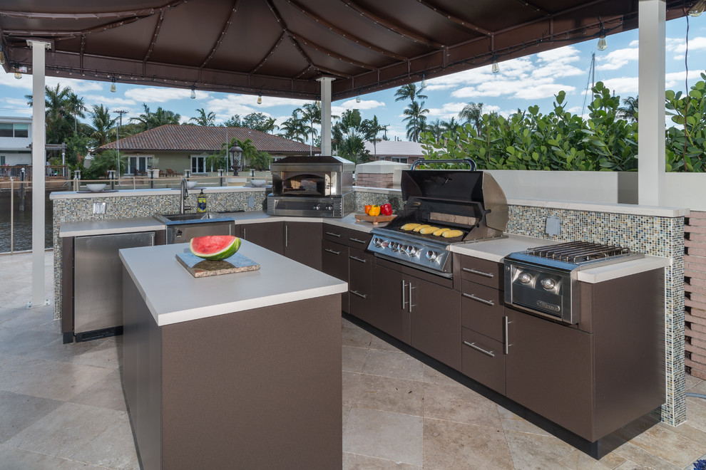 Small tropical backyard patio in Miami with an outdoor kitchen, an awning and brick pavers.
