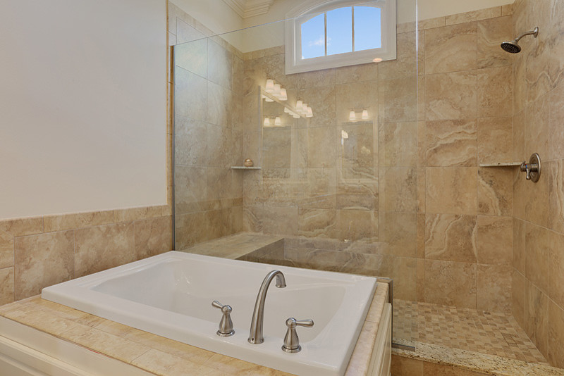 Large transitional master bathroom in New Orleans with raised-panel cabinets, white cabinets, a drop-in tub, an alcove shower, beige tile, white walls, ceramic floors and granite benchtops.