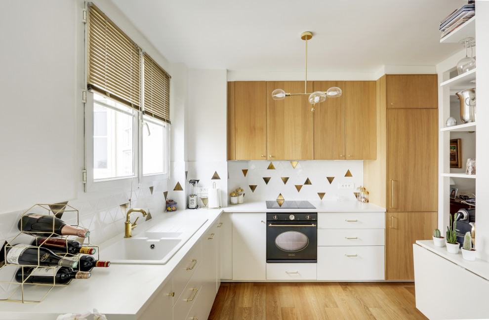 This is an example of a mid-sized contemporary l-shaped kitchen in Paris with a drop-in sink, flat-panel cabinets, white cabinets, multi-coloured splashback, panelled appliances, medium hardwood floors, beige floor and white benchtop.