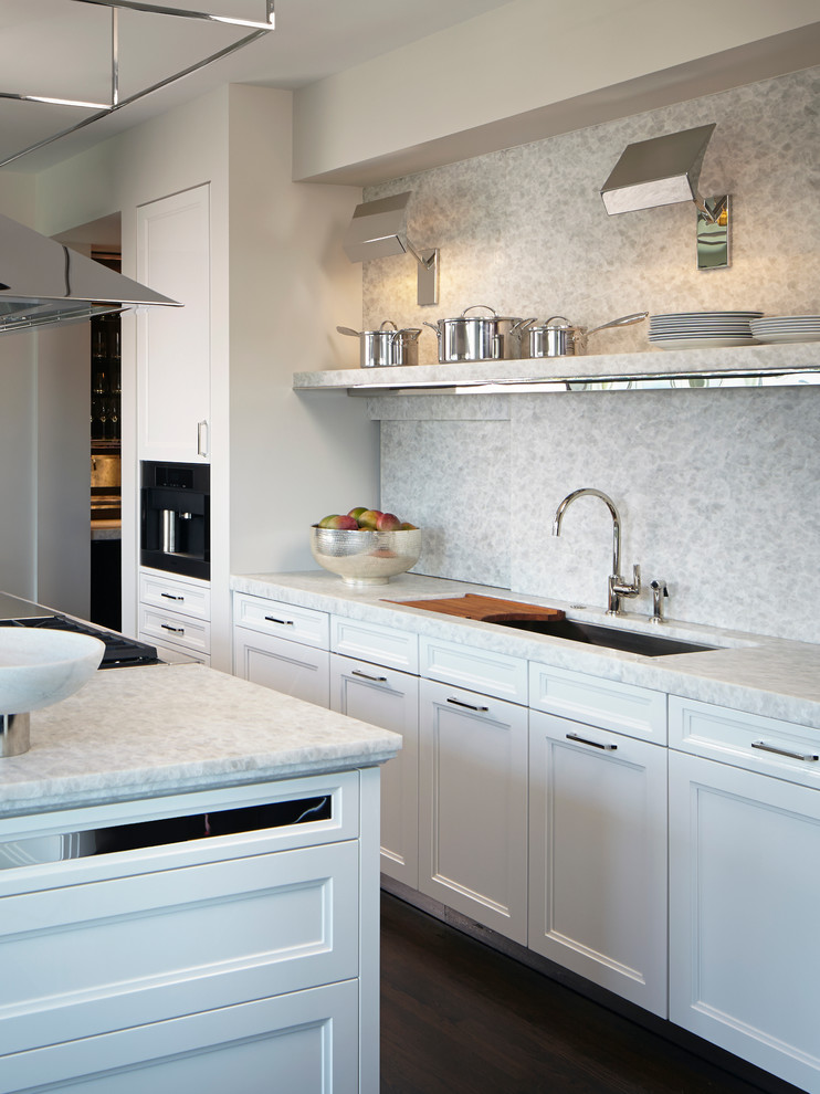 Inspiration for a mid-sized transitional galley dark wood floor enclosed kitchen remodel in Chicago with an undermount sink, recessed-panel cabinets, white cabinets, quartzite countertops, white backsplash, stone slab backsplash, stainless steel appliances and an island