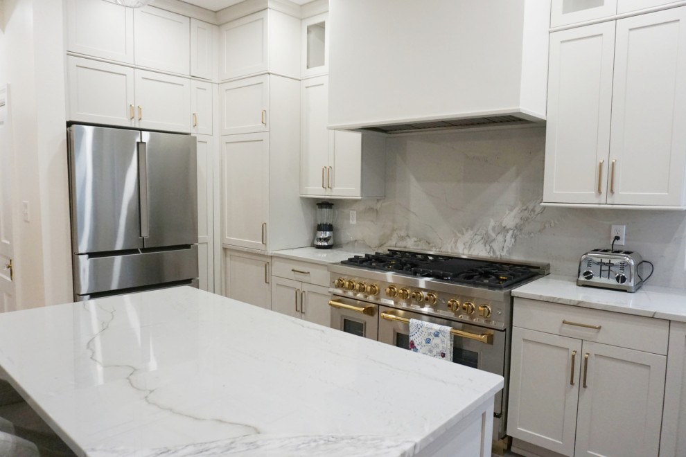 Example of a transitional vinyl floor and gray floor kitchen design with an undermount sink, shaker cabinets, gray cabinets, quartzite countertops, stone slab backsplash, stainless steel appliances and an island