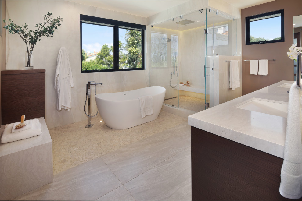 Idée de décoration pour une grande salle de bain principale design en bois foncé avec un placard à porte plane, un plan de toilette en quartz modifié, un plan de toilette blanc, meuble double vasque, meuble-lavabo suspendu, une baignoire indépendante, une douche d'angle, un carrelage blanc, une plaque de galets, un mur blanc, un sol en marbre, un lavabo encastré, un sol blanc et une cabine de douche à porte battante.