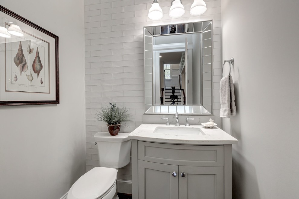 Design ideas for a mid-sized country powder room in DC Metro with recessed-panel cabinets, grey cabinets, a two-piece toilet, white tile, subway tile, grey walls, an undermount sink, quartzite benchtops and white benchtops.