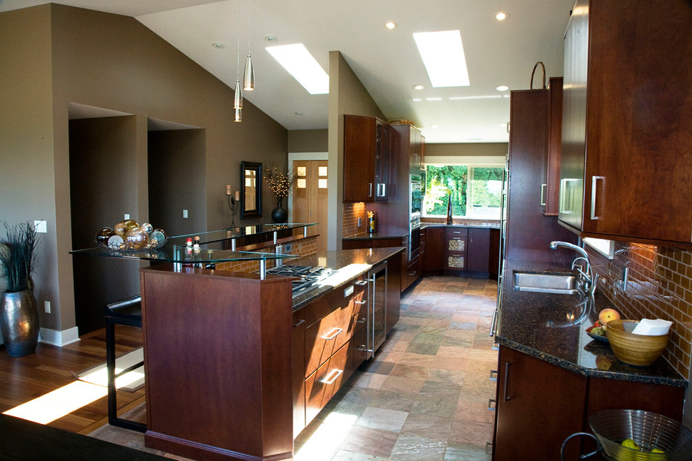Large modern u-shaped open plan kitchen in Seattle with a double-bowl sink, flat-panel cabinets, dark wood cabinets, granite benchtops, brown splashback, glass tile splashback, stainless steel appliances, slate floors and with island.