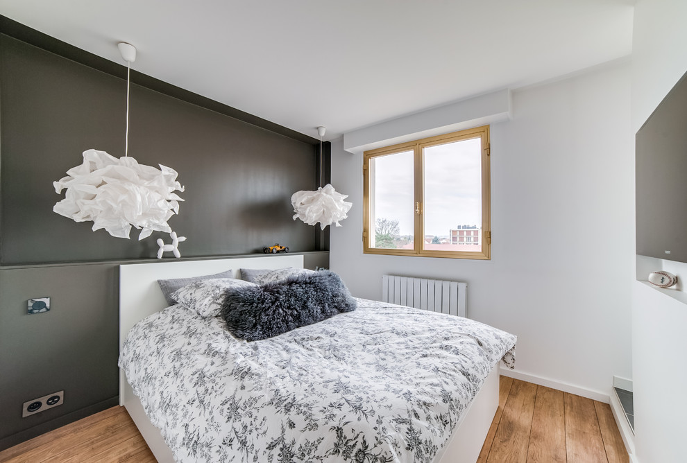 Photo of a contemporary bedroom in Paris with grey walls, medium hardwood floors and brown floor.