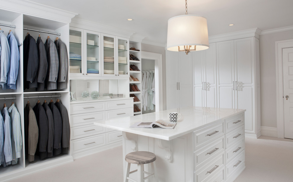 Large contemporary gender-neutral dressing room in New York with recessed-panel cabinets, white cabinets and carpet.