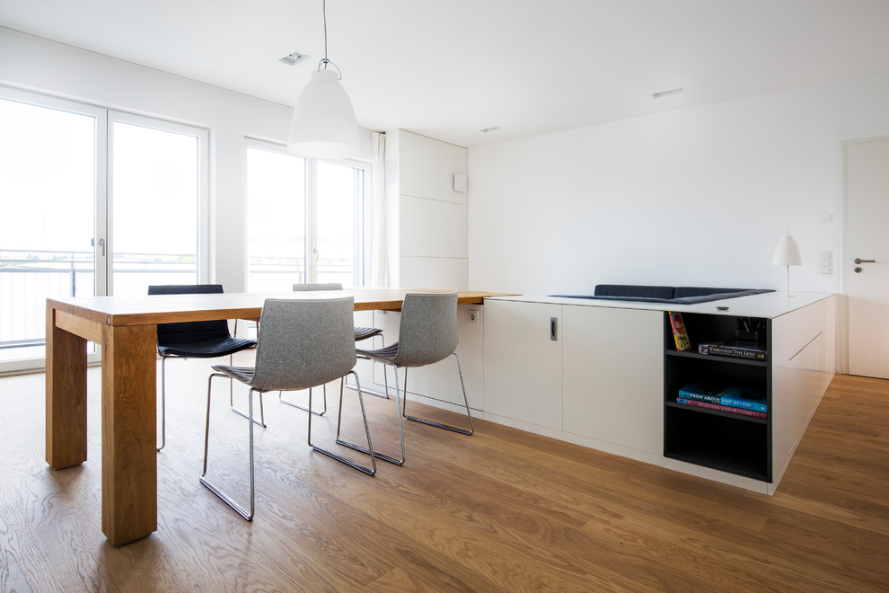 This is an example of a mid-sized contemporary open plan dining in Munich with white walls, medium hardwood floors and brown floor.