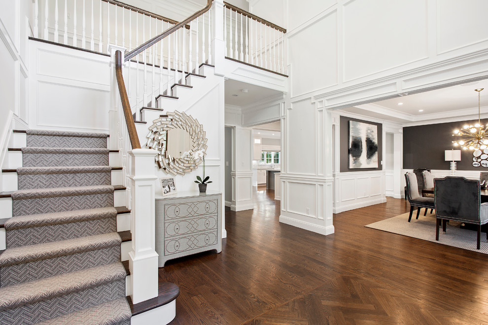 Design ideas for a transitional foyer in New York with white walls, dark hardwood floors and brown floor.