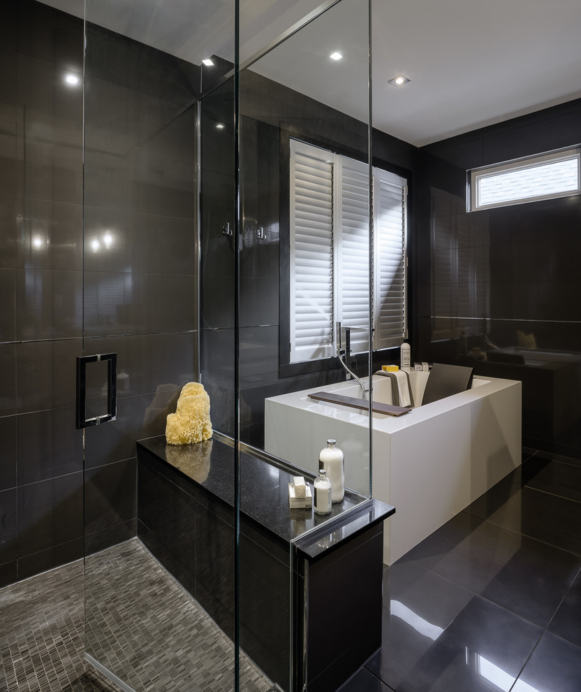 This is an example of a large contemporary master bathroom in Ottawa with flat-panel cabinets, medium wood cabinets, a freestanding tub, a corner shower, a one-piece toilet, black tile, porcelain tile and black walls.