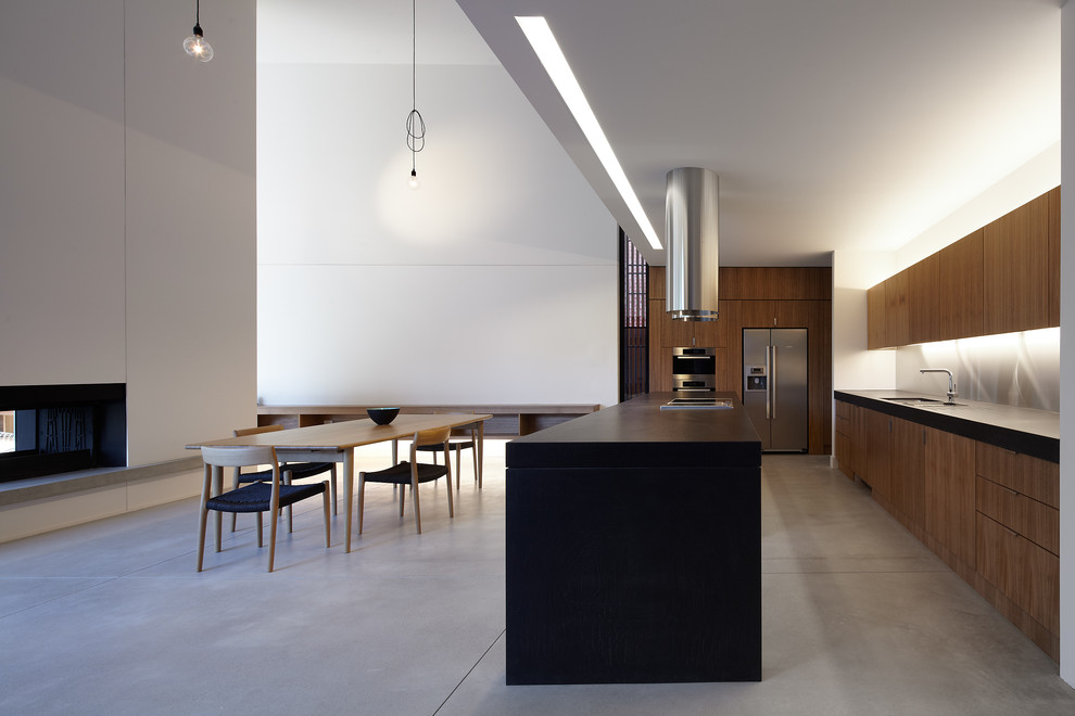 Design ideas for a contemporary u-shaped kitchen in Melbourne with an undermount sink, flat-panel cabinets, medium wood cabinets, quartz benchtops, metallic splashback, stainless steel appliances, concrete floors and with island.
