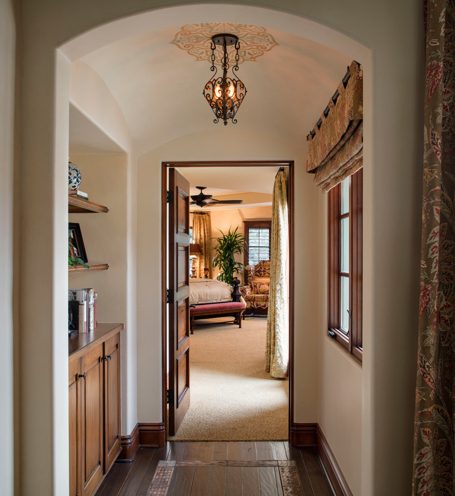 Inspiration for a mid-sized mediterranean hallway in San Diego with dark hardwood floors and beige walls.