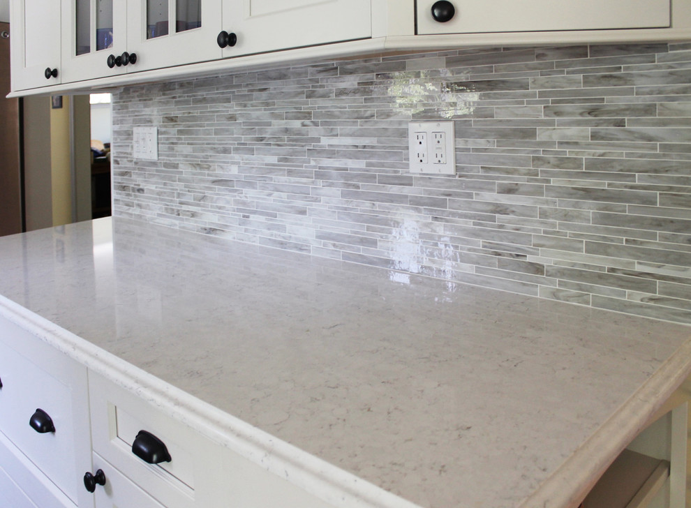 Mid-sized transitional galley light wood floor and brown floor enclosed kitchen photo in New York with an undermount sink, recessed-panel cabinets, white cabinets, marble countertops, beige backsplash, matchstick tile backsplash, stainless steel appliances and no island