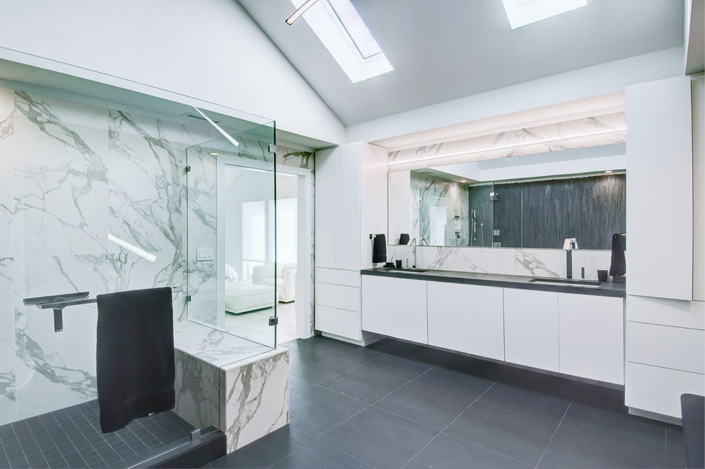 Design ideas for an expansive contemporary master bathroom in Charleston with flat-panel cabinets, white cabinets, a freestanding tub, a corner shower, white tile, marble, grey walls, an undermount sink, solid surface benchtops, grey floor and a hinged shower door.