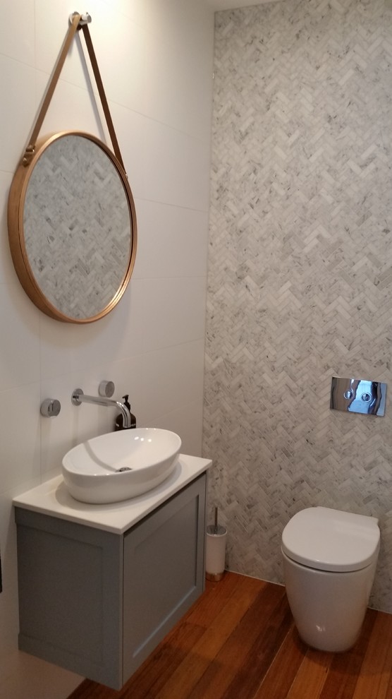 Small scandinavian bathroom in Melbourne with shaker cabinets, grey cabinets, a drop-in tub, a corner shower, a wall-mount toilet, white tile, ceramic tile, white walls, slate floors, a vessel sink, marble benchtops, grey floor, a hinged shower door and white benchtops.