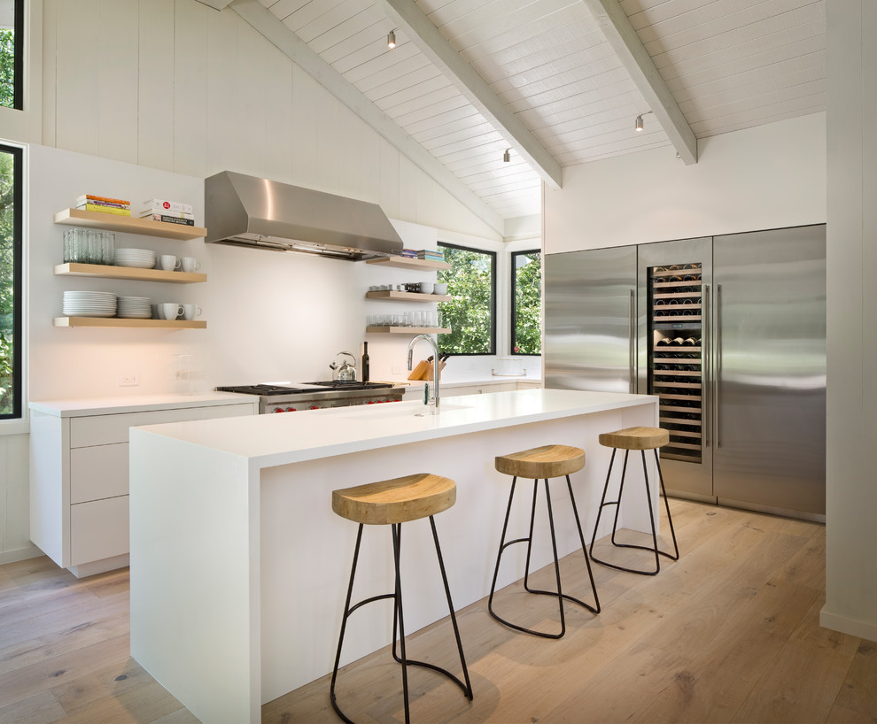 Large contemporary l-shaped kitchen in Other with an undermount sink, flat-panel cabinets, white cabinets, quartz benchtops, white splashback, stainless steel appliances, medium hardwood floors, with island and brown floor.