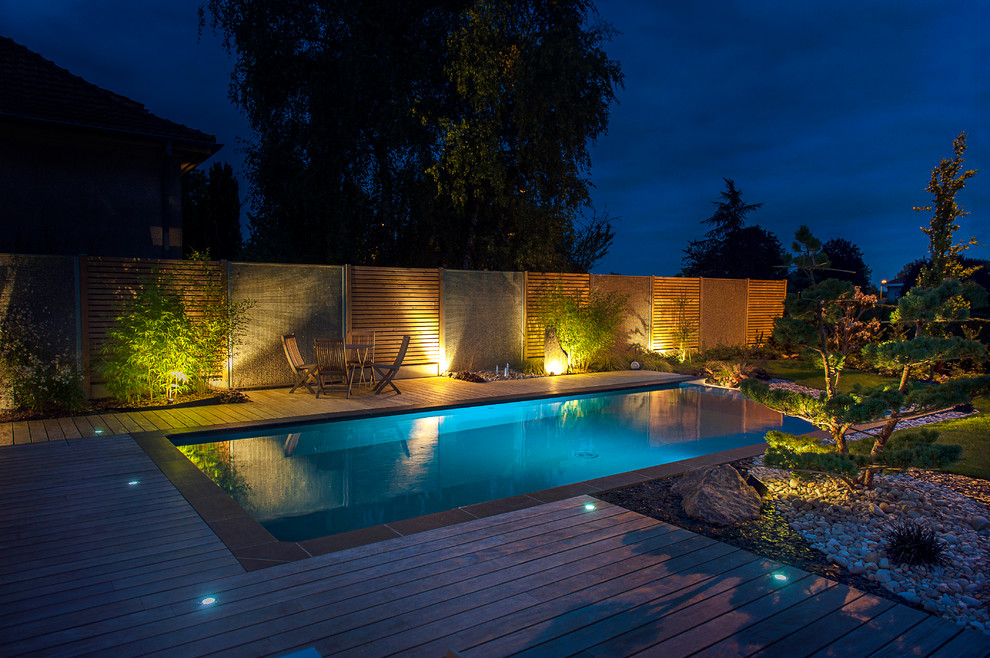 Design ideas for a large contemporary backyard rectangular infinity pool in Paris with decking.