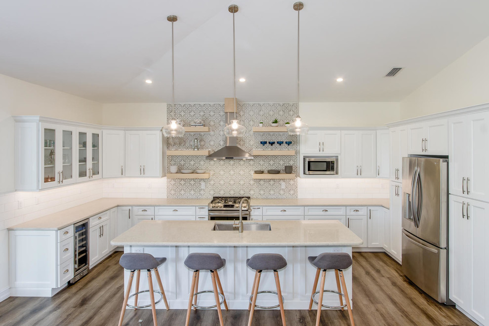 Beach style u-shaped kitchen in Other with an undermount sink, shaker cabinets, white cabinets, grey splashback, cement tile splashback, stainless steel appliances, medium hardwood floors, with island and brown floor.