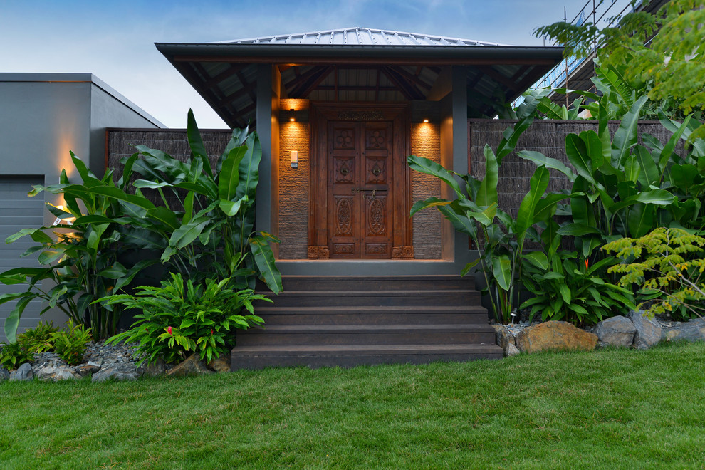 This is an example of a tropical front door in Cairns with grey walls, a double front door and a medium wood front door.