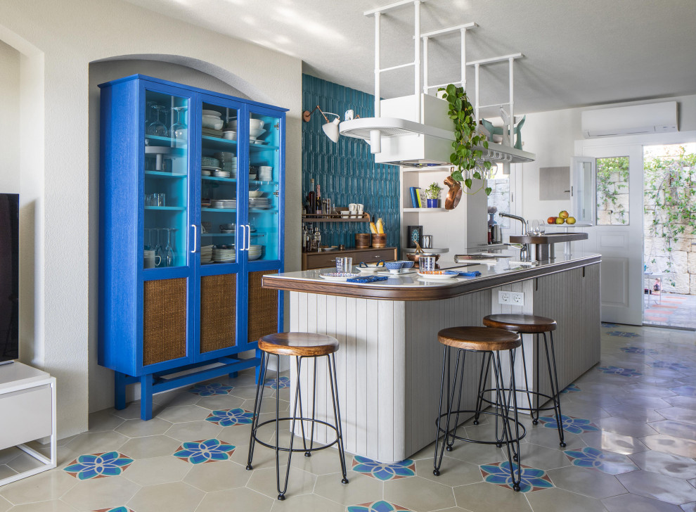 Idéer för små medelhavsstil vitt kök, med en nedsänkt diskho, blå skåp, bänkskiva i kvartsit, blått stänkskydd, stänkskydd i keramik, integrerade vitvaror, cementgolv, en köksö och turkost golv