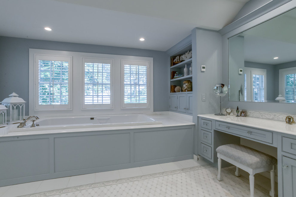 This is an example of a large traditional master bathroom in New York with beaded inset cabinets, blue cabinets, a drop-in tub, a corner shower, a bidet, white tile, blue walls, mosaic tile floors, an undermount sink, quartzite benchtops, white floor and a hinged shower door.