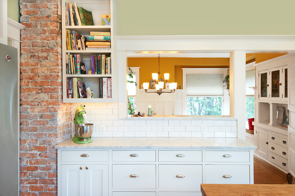 This is an example of a mid-sized country u-shaped separate kitchen in Seattle with a farmhouse sink, shaker cabinets, white cabinets, wood benchtops, white splashback, subway tile splashback, stainless steel appliances, carpet, with island, brown floor and brown benchtop.