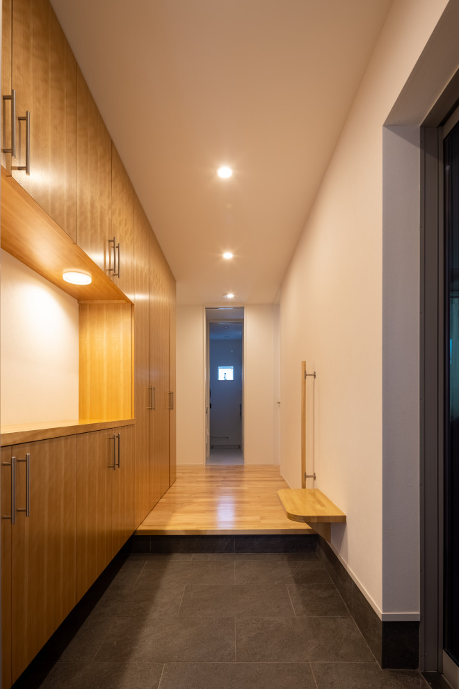 Moderner Eingang mit Korridor, weißer Wandfarbe, Terrakottaboden, Einzeltür, Haustür aus Metall, schwarzem Boden, Tapetendecke und Tapetenwänden in Tokio Peripherie