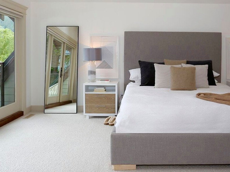 Large beach style master bedroom in Vancouver with white walls, carpet and beige floor.