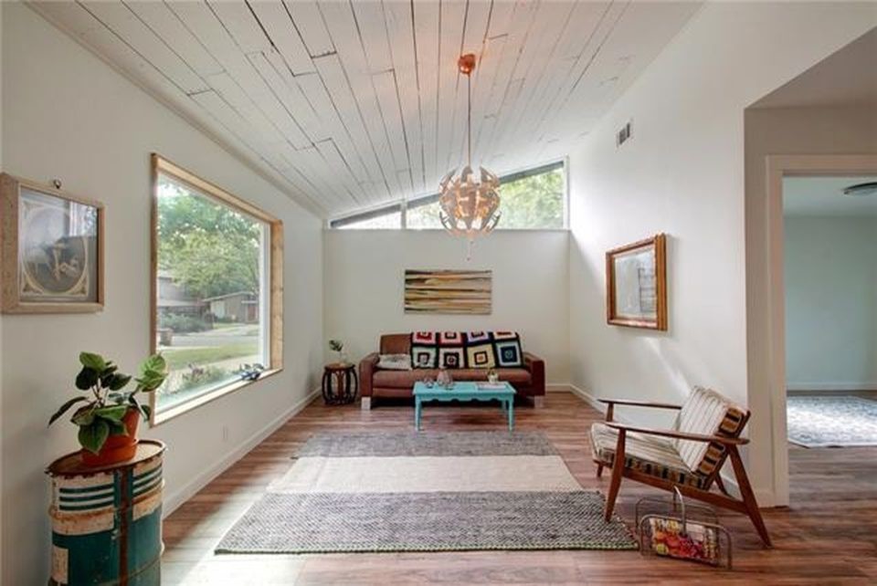 This is an example of a mid-sized midcentury open concept living room in Austin with white walls, laminate floors and brown floor.