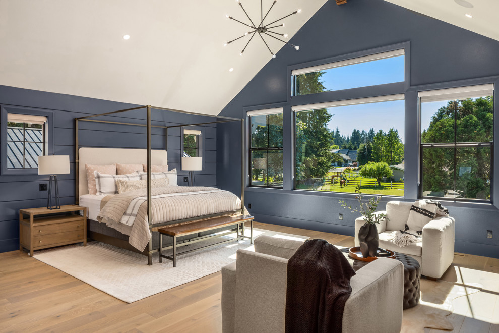 This is an example of an expansive transitional bedroom in Seattle with blue walls, light hardwood floors, a standard fireplace, vaulted and planked wall panelling.