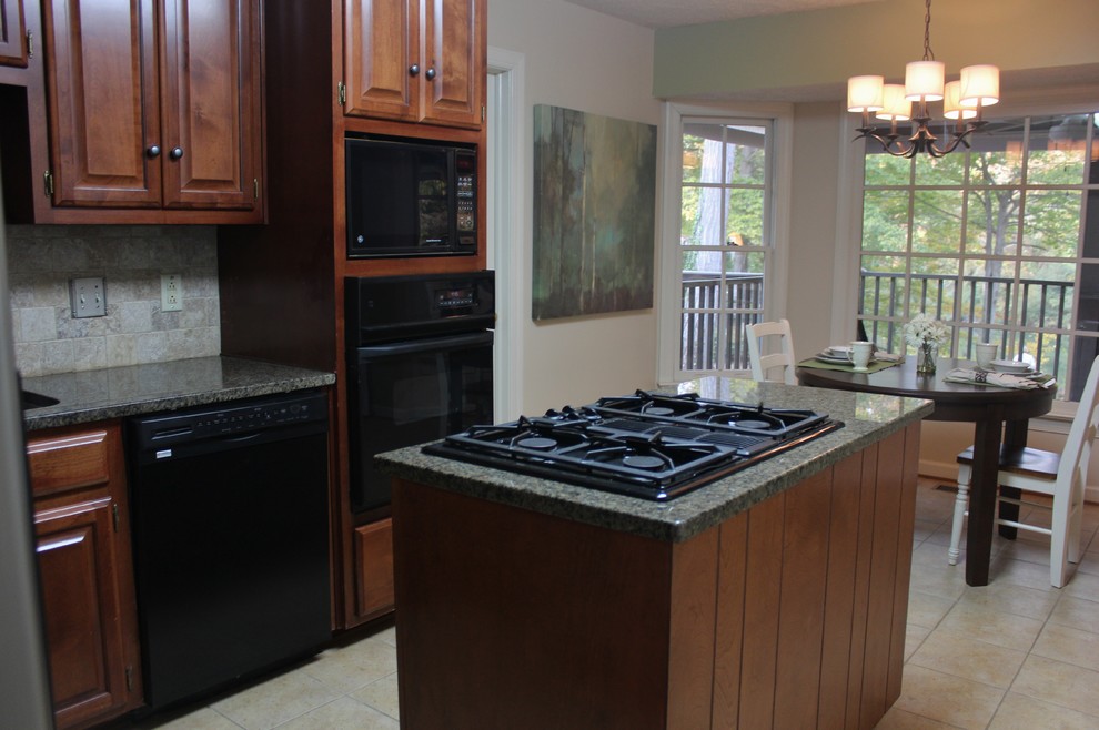 Transitional l-shaped porcelain tile kitchen photo with an undermount sink, raised-panel cabinets, medium tone wood cabinets, granite countertops, beige backsplash, stone tile backsplash, black appliances and an island