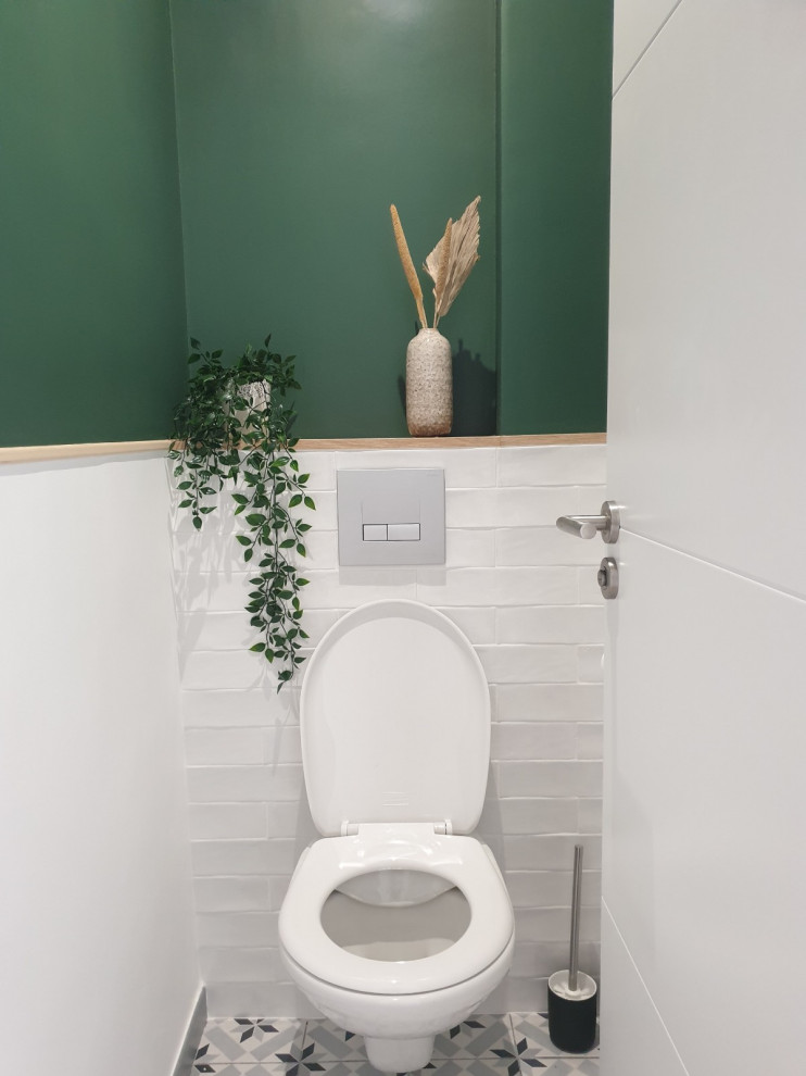 Mittelgroße Moderne Gästetoilette mit Wandtoilette, weißen Fliesen, Keramikfliesen, grüner Wandfarbe, Zementfliesen für Boden, Waschtisch aus Holz, grauem Boden und grüner Waschtischplatte in Paris