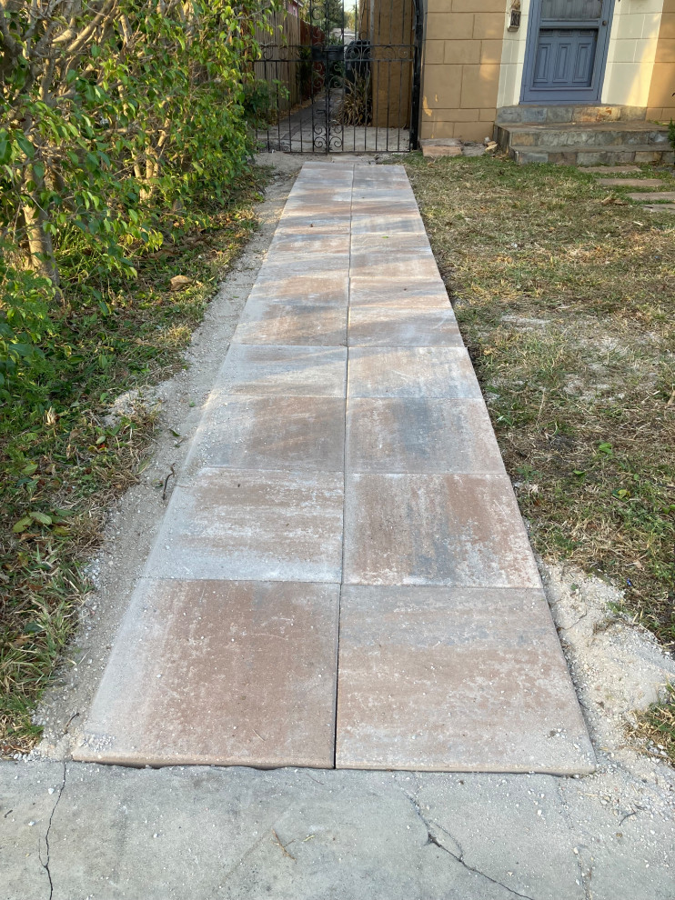This is an example of a mid-sized side yard full sun xeriscape for summer in Miami with a garden path and natural stone pavers.