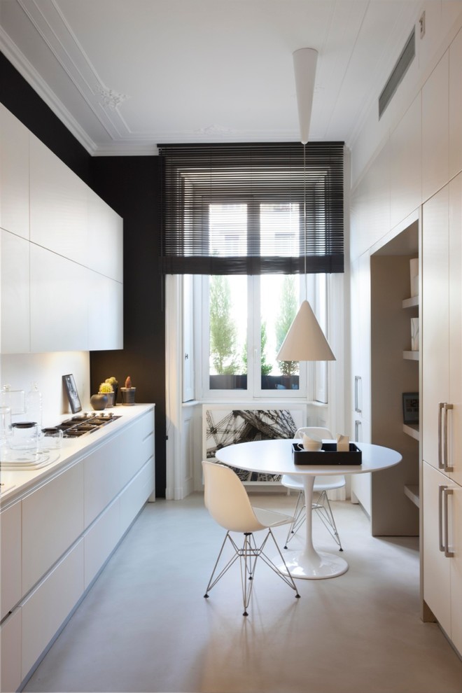 Photo of a mid-sized contemporary galley separate kitchen in Milan with an integrated sink, stainless steel appliances, concrete floors, no island, beige floor, flat-panel cabinets and white splashback.