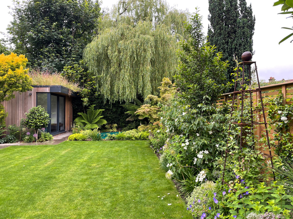 Geometrischer, Großer Moderner Garten im Sommer, hinter dem Haus mit direkter Sonneneinstrahlung, Natursteinplatten und Holzzaun in London
