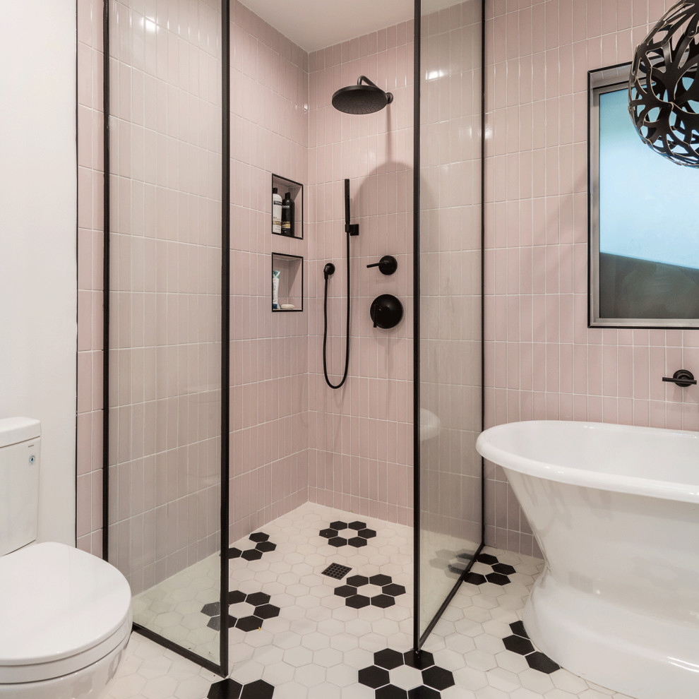 Пример оригинального дизайна: ванная комната в стиле шебби-шик с плоскими фасадами, фасадами цвета дерева среднего тона, отдельно стоящей ванной, угловым душем, розовой плиткой, стеклянной плиткой, белыми стенами, полом из керамической плитки, накладной раковиной, столешницей из известняка, разноцветным полом, открытым душем, белой столешницей, тумбой под две раковины и подвесной тумбой
