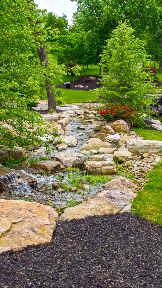 Photo of a large backyard formal garden in Other with a water feature.
