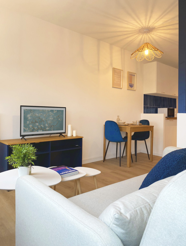 Ejemplo de salón abierto minimalista de tamaño medio sin chimenea con paredes blancas, suelo laminado, televisor independiente y suelo beige