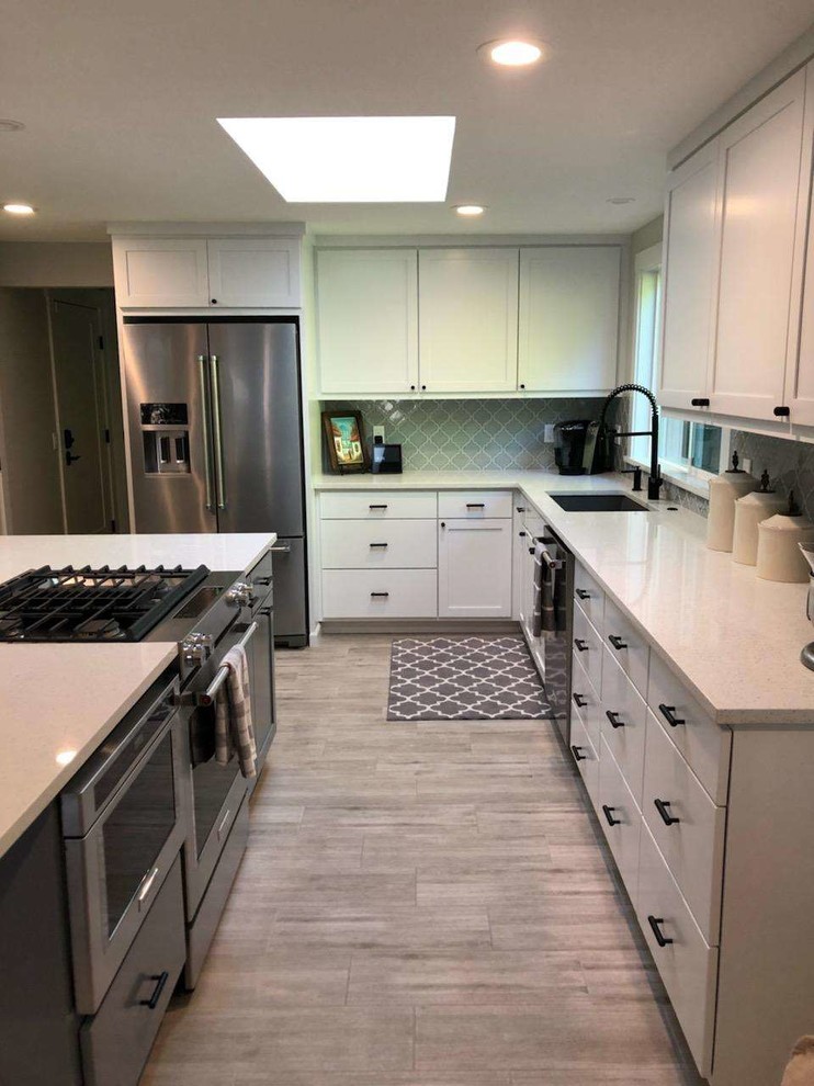 Example of a mid-sized transitional u-shaped porcelain tile and gray floor eat-in kitchen design in Seattle with an undermount sink, recessed-panel cabinets, white cabinets, quartzite countertops, gray backsplash, ceramic backsplash, stainless steel appliances, an island and white countertops