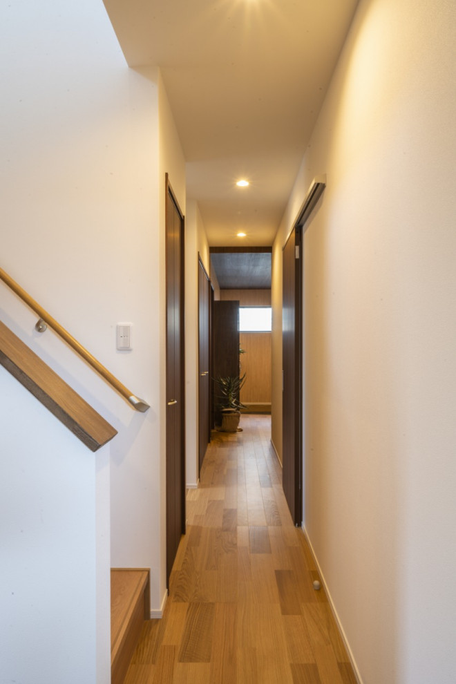 Photo of a mid-sized contemporary hallway in Other with light hardwood floors, beige floor and wallpaper.