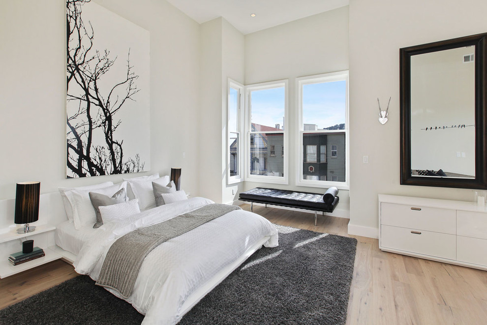 Photo of a large contemporary master bedroom in San Francisco with white walls and light hardwood floors.