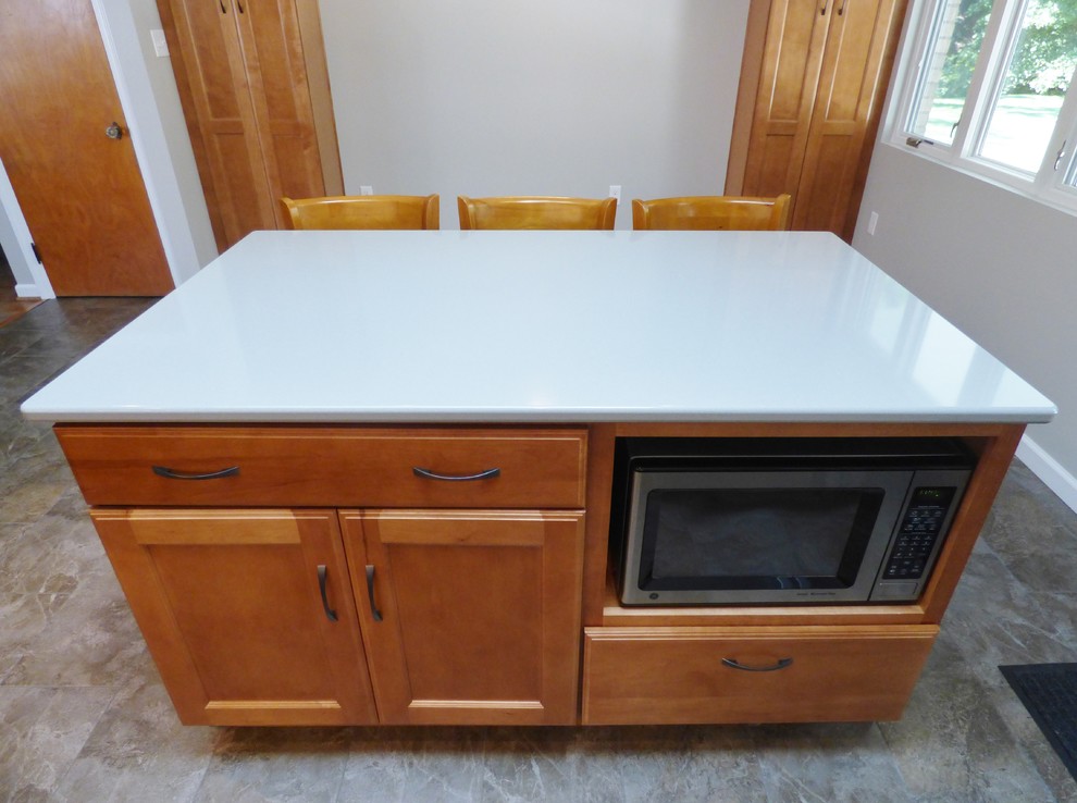 Transitional l-shaped porcelain tile eat-in kitchen photo with an undermount sink, recessed-panel cabinets, medium tone wood cabinets, quartz countertops, white backsplash, subway tile backsplash, stainless steel appliances and an island