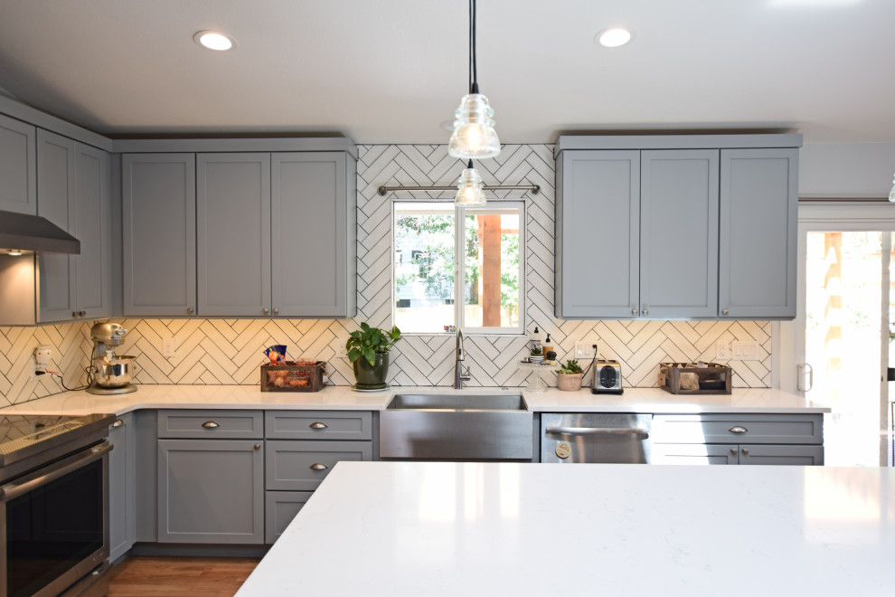 Inspiration for a mid-sized transitional l-shaped vaulted ceiling open concept kitchen remodel in Denver with a farmhouse sink, shaker cabinets, gray cabinets, quartz countertops, white backsplash, stainless steel appliances, an island and white countertops