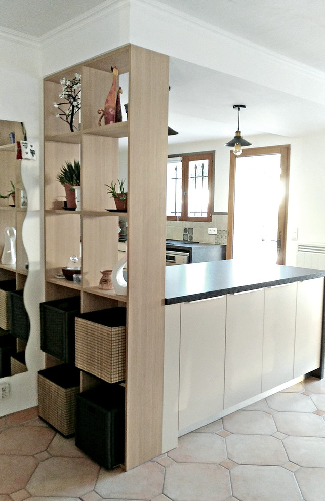 This is an example of a large industrial l-shaped eat-in kitchen in Other with a single-bowl sink, beaded inset cabinets, beige cabinets, laminate benchtops, multi-coloured splashback, cement tile splashback, black appliances, ceramic floors, with island, beige floor and grey benchtop.