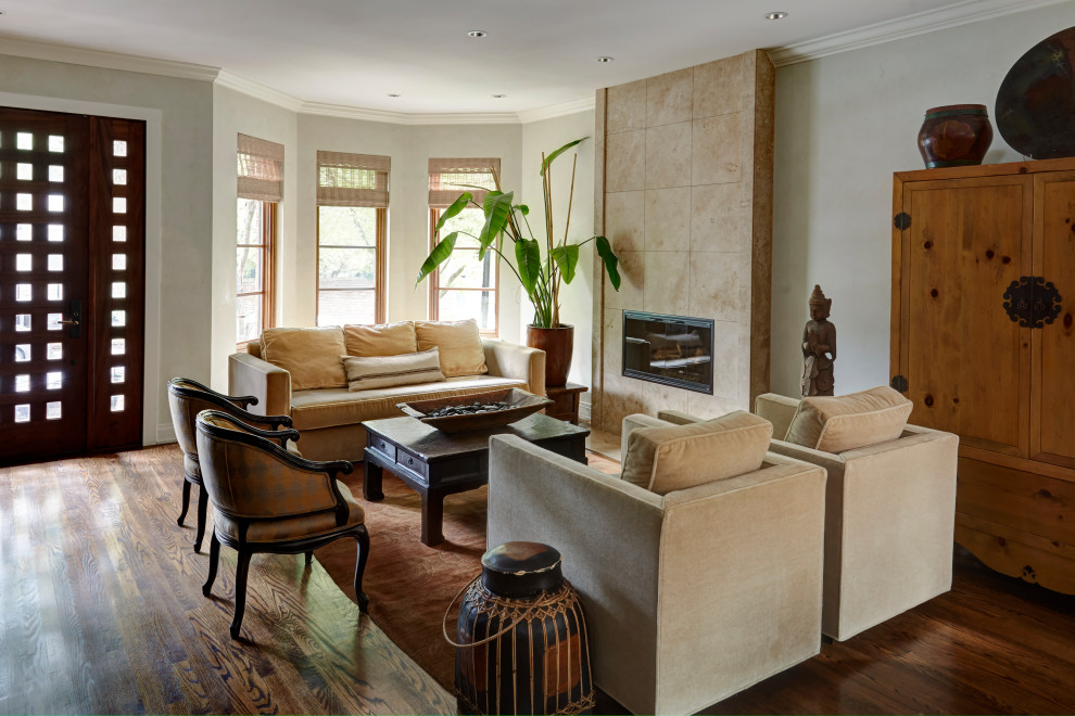 Пример оригинального дизайна: гостиная комната в восточном стиле с серыми стенами, темным паркетным полом, стандартным камином, фасадом камина из плитки и коричневым полом