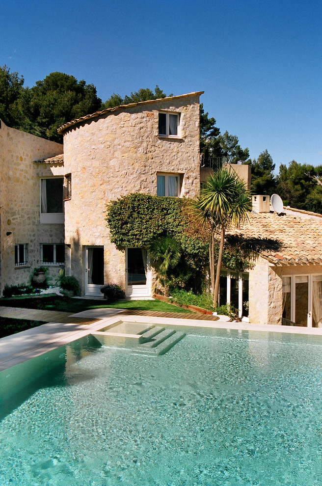 This is an example of a mid-sized mediterranean three-storey beige exterior in Nice with stone veneer and a shed roof.